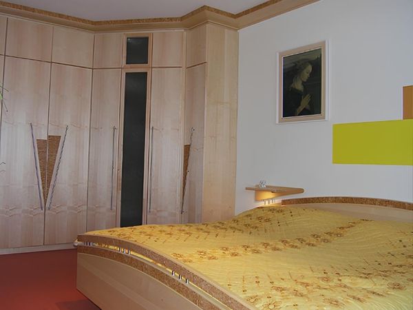 Ein Bett und ein Schrank aus hellem Holz